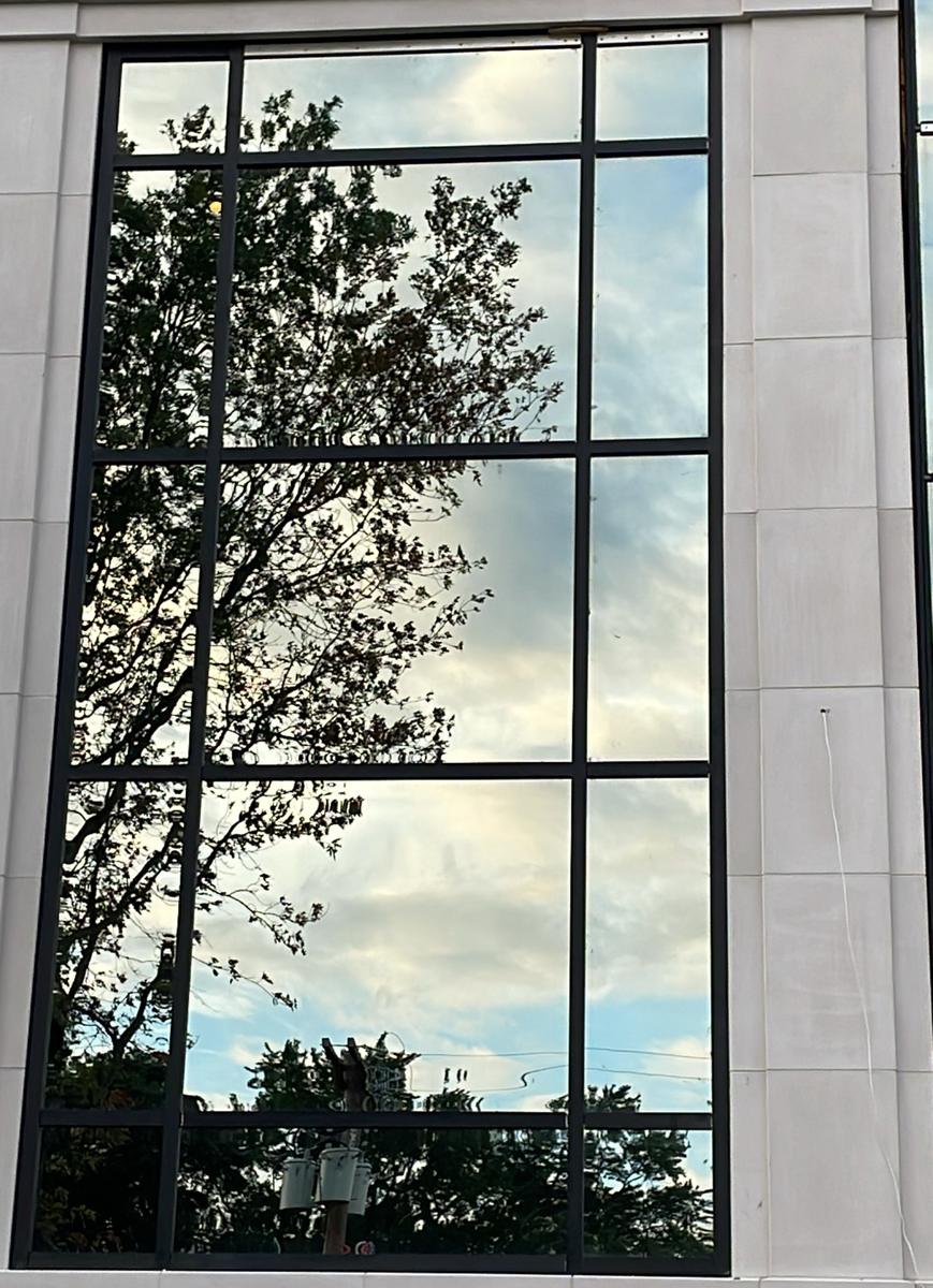 Tall commercial window with black mullions on a limestone facade