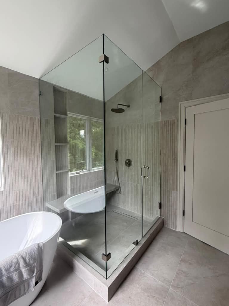 Corner frameless shower under a vaulted ceiling beside a freestanding tub