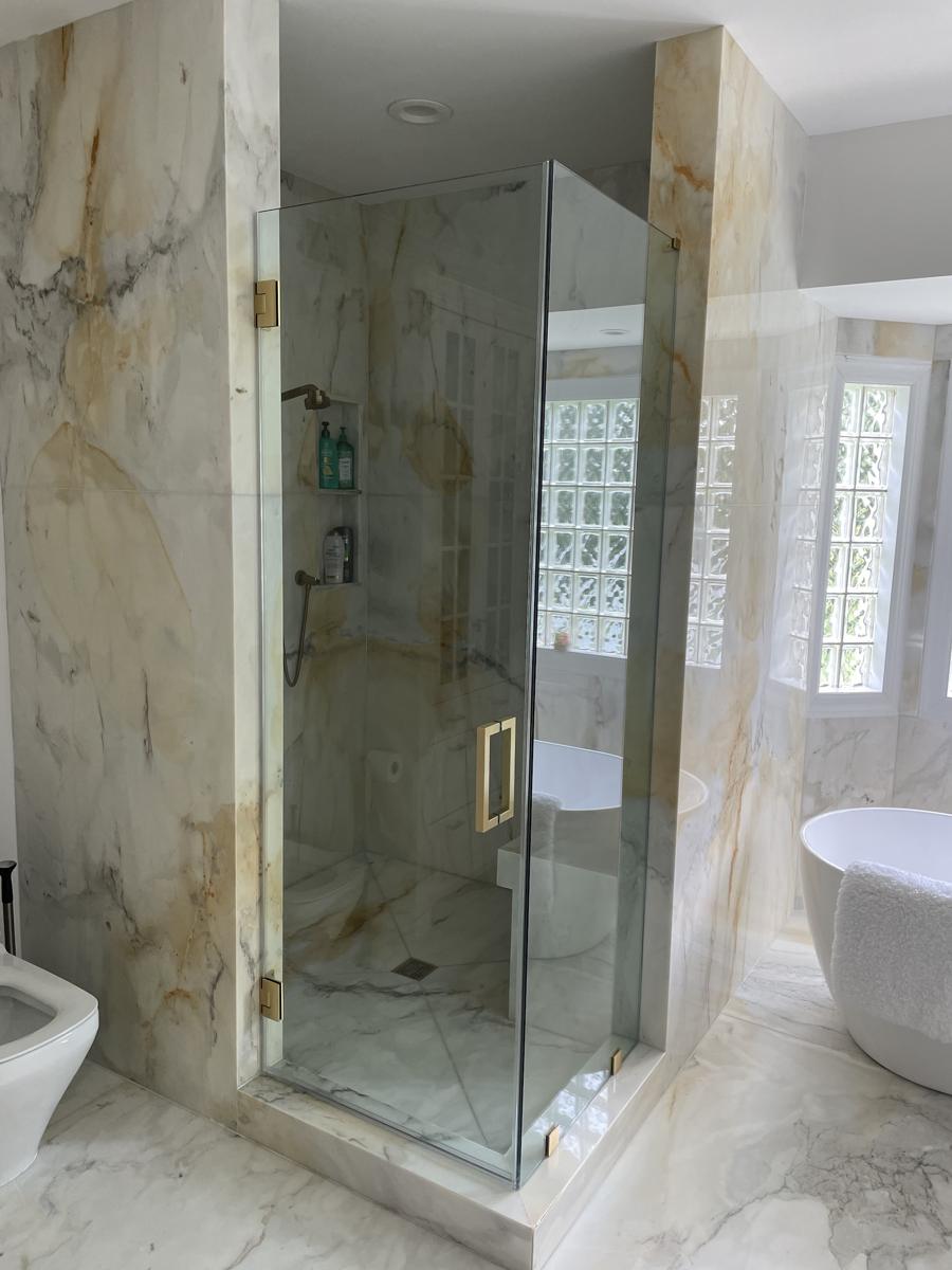 Corner frameless shower with brushed gold hinges