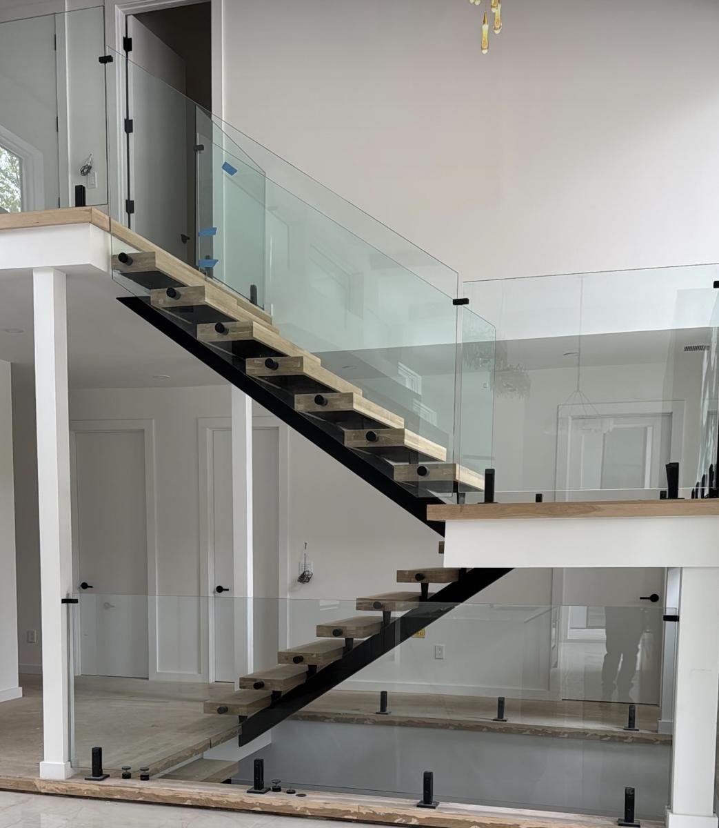 Floating staircase with frameless glass railing and black spigots