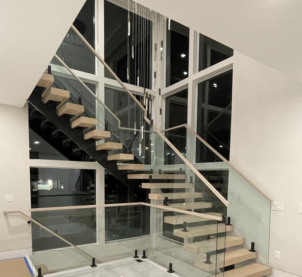Floating staircase with frameless glass railing and white oak handrail