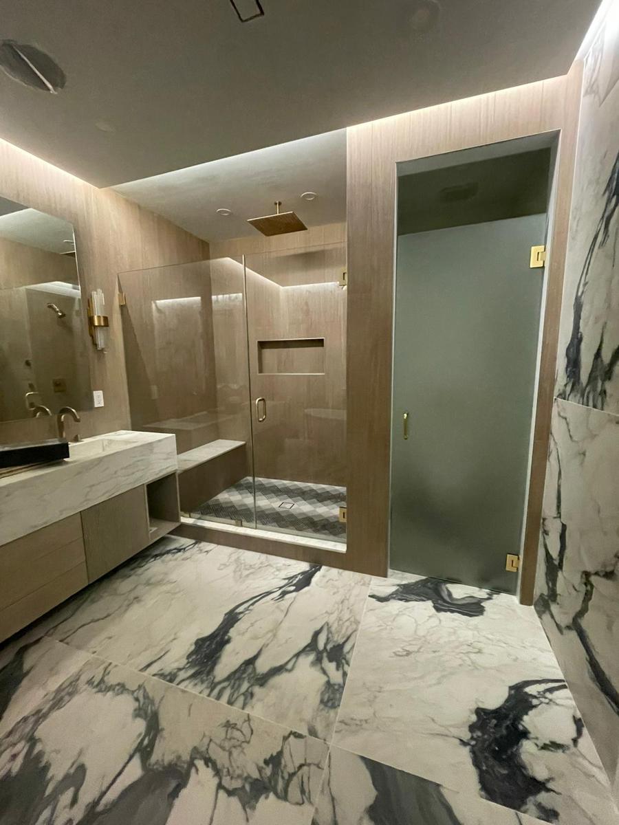 Frameless shower and frosted water closet door with brushed gold hardware