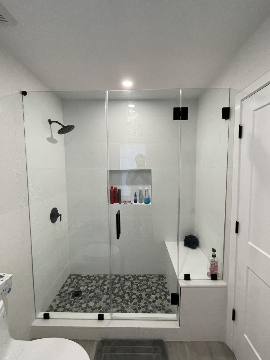 Frameless shower door and panels over a bench, matte black