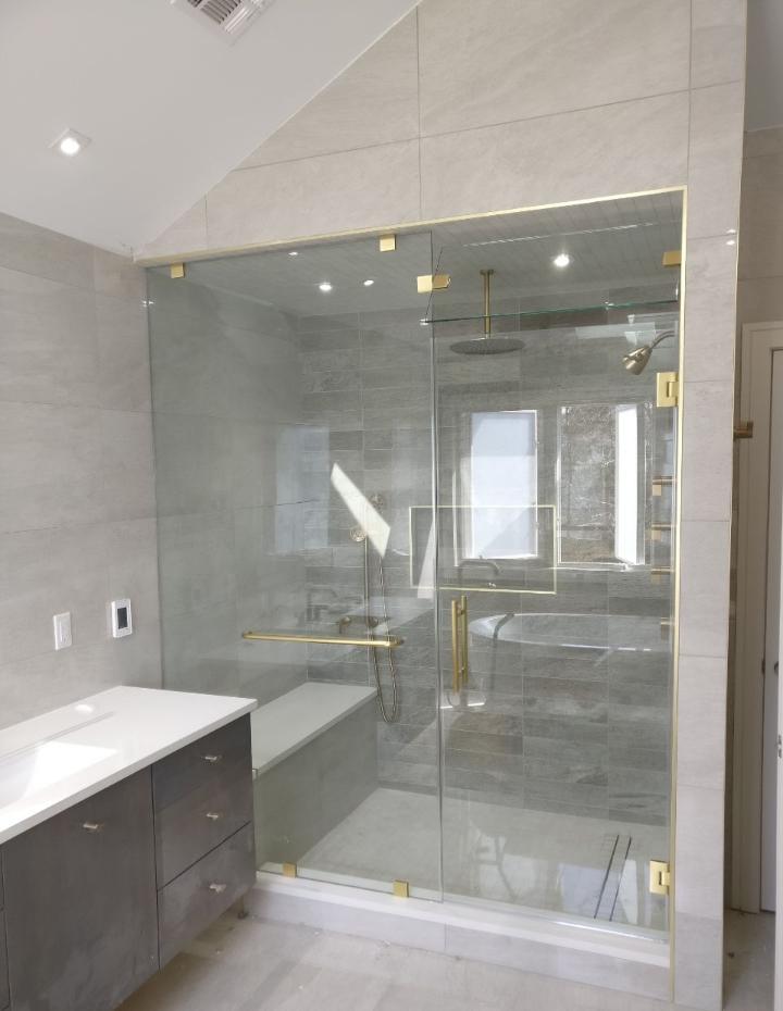 Frameless enclosure with gold hardware and transom