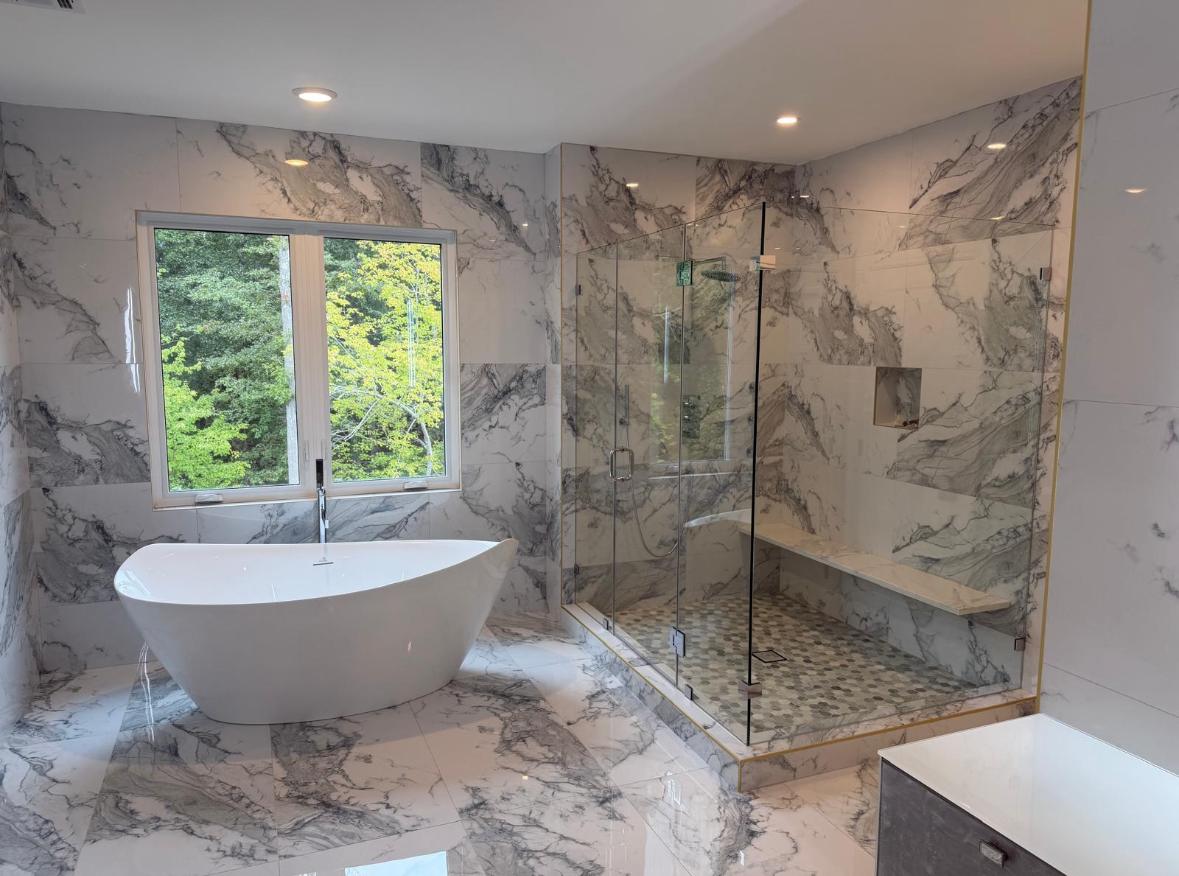Frameless shower enclosure with bench in a marble bathroom