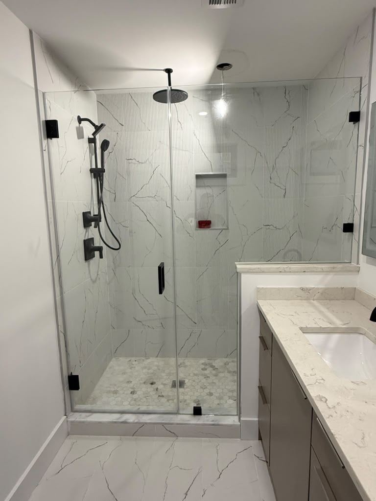 Frameless shower door with matte black hardware and marble tile