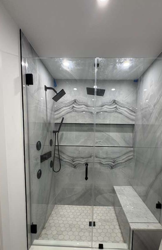 Frameless shower with matte black hardware, onyx-look tile and bench