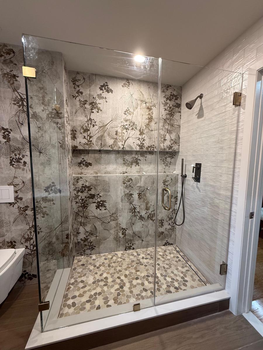 Frameless shower enclosure with brass hinges and pebble floor