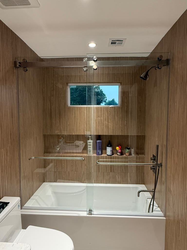 Frameless sliding tub door with brushed nickel barn-style hardware