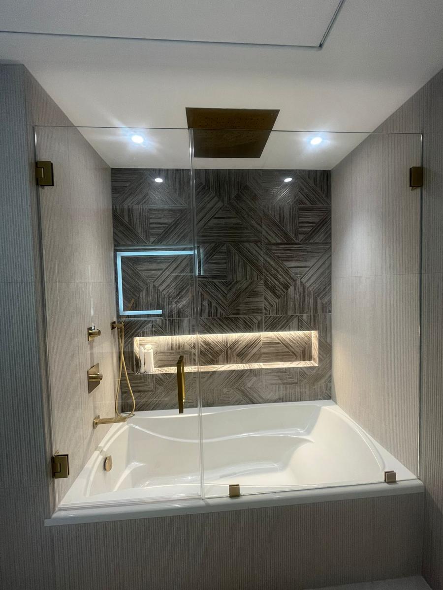 Frameless tub door and panel with brushed gold hinges