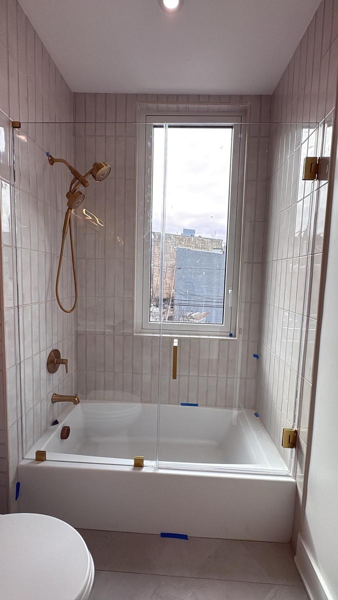 Frameless glass door and panel on a bathtub with gold hinges