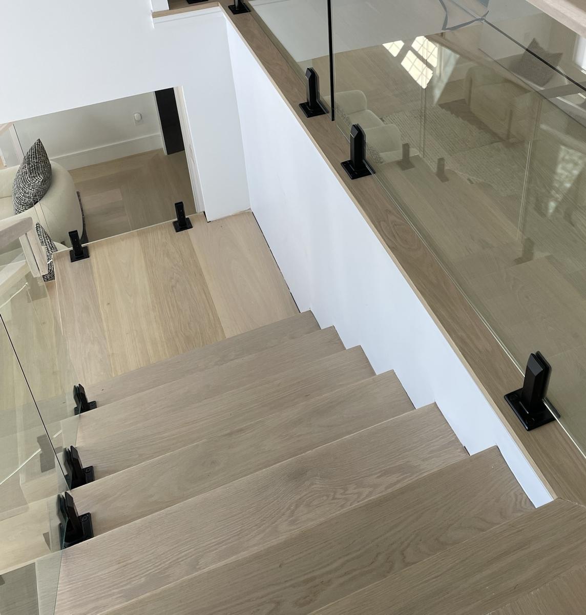 Glass landing railing with white oak cap and black spigots