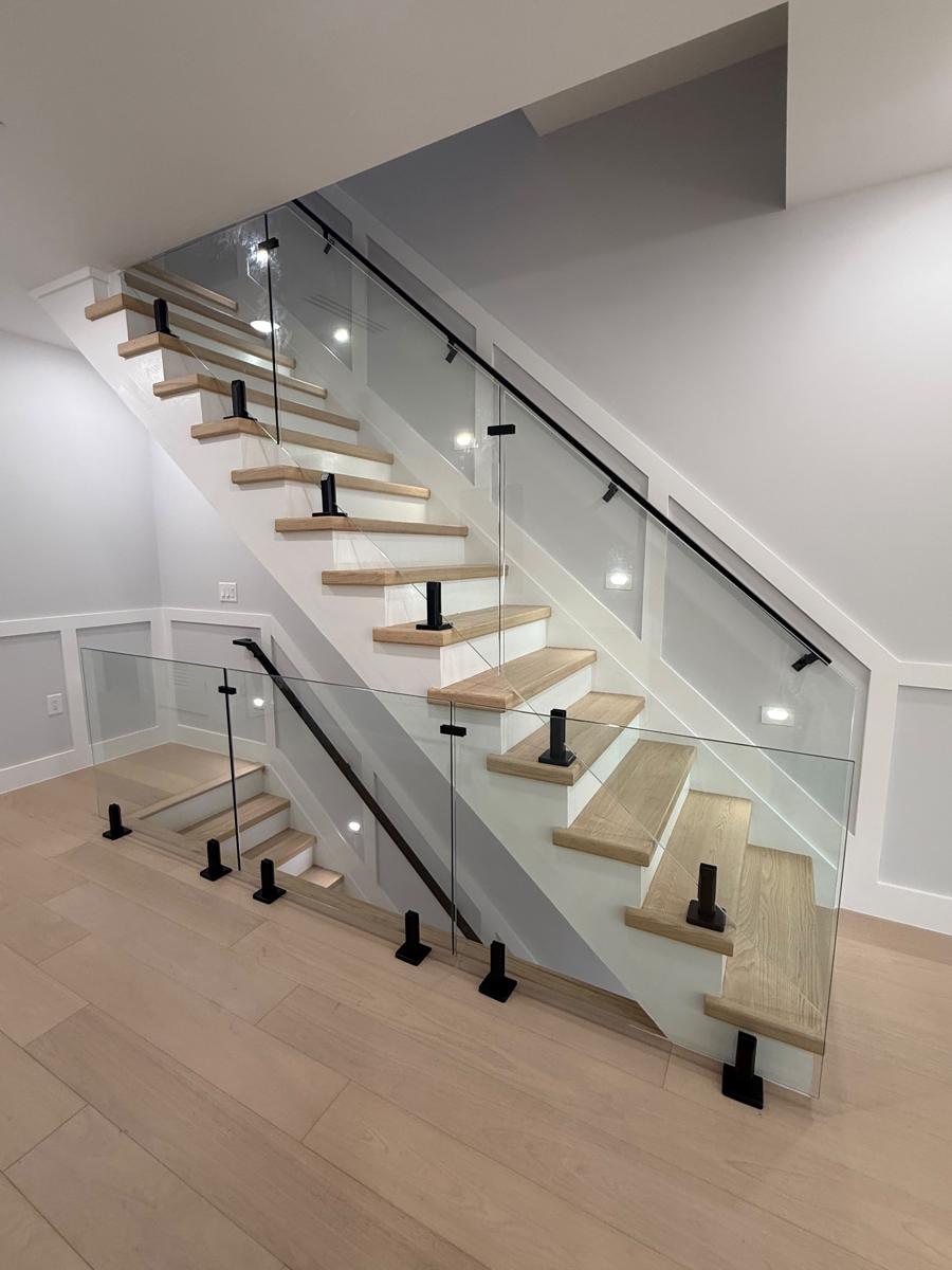 Glass stair railing with black spigots on oak stairs