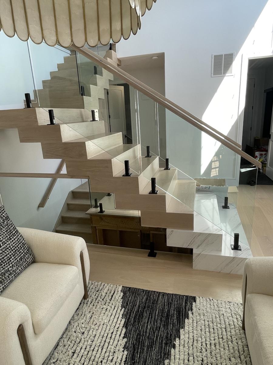 Frameless glass stair railing with black spigots and white oak handrail