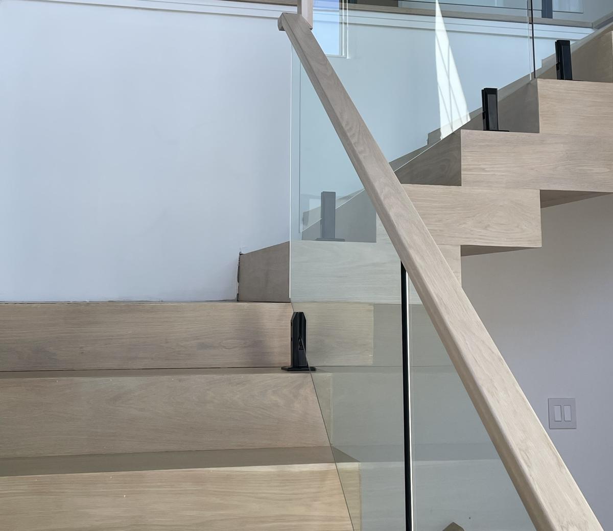 Glass stair railing with a white oak handrail