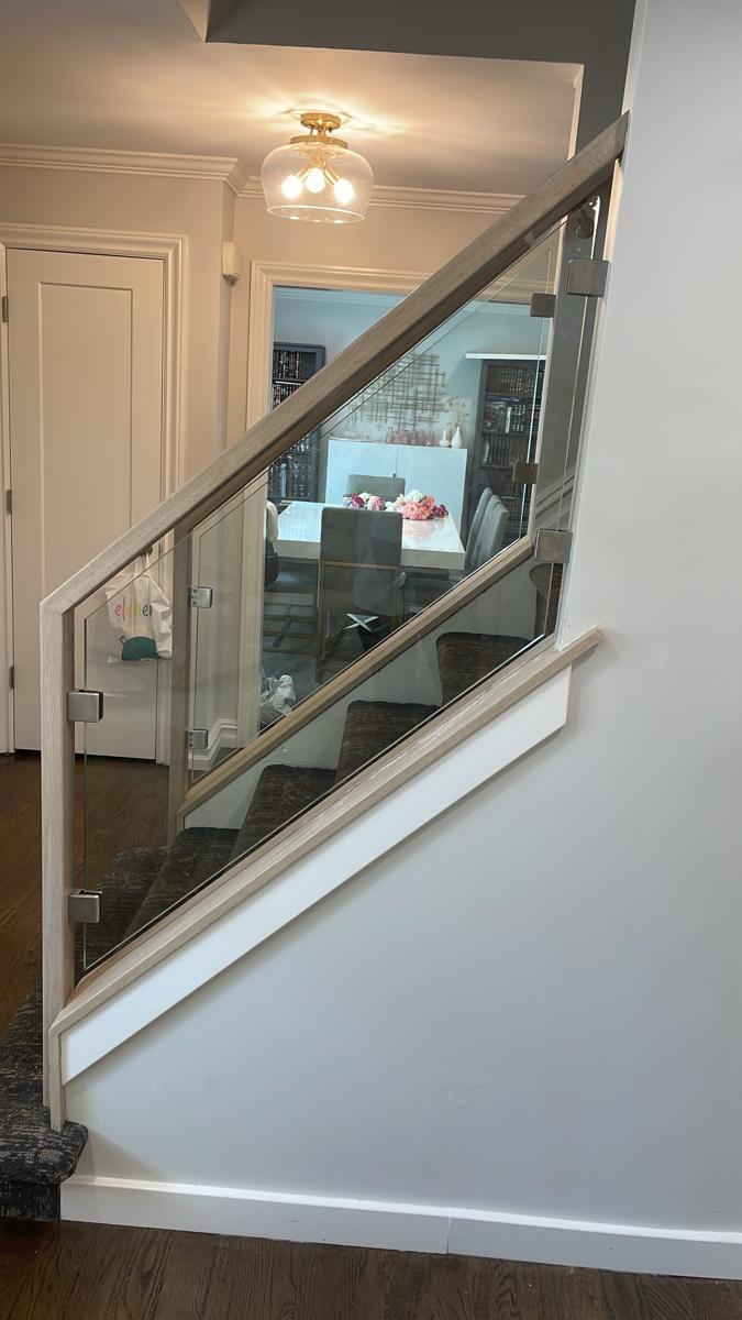 Glass stair railing in a wood frame with stainless clips
