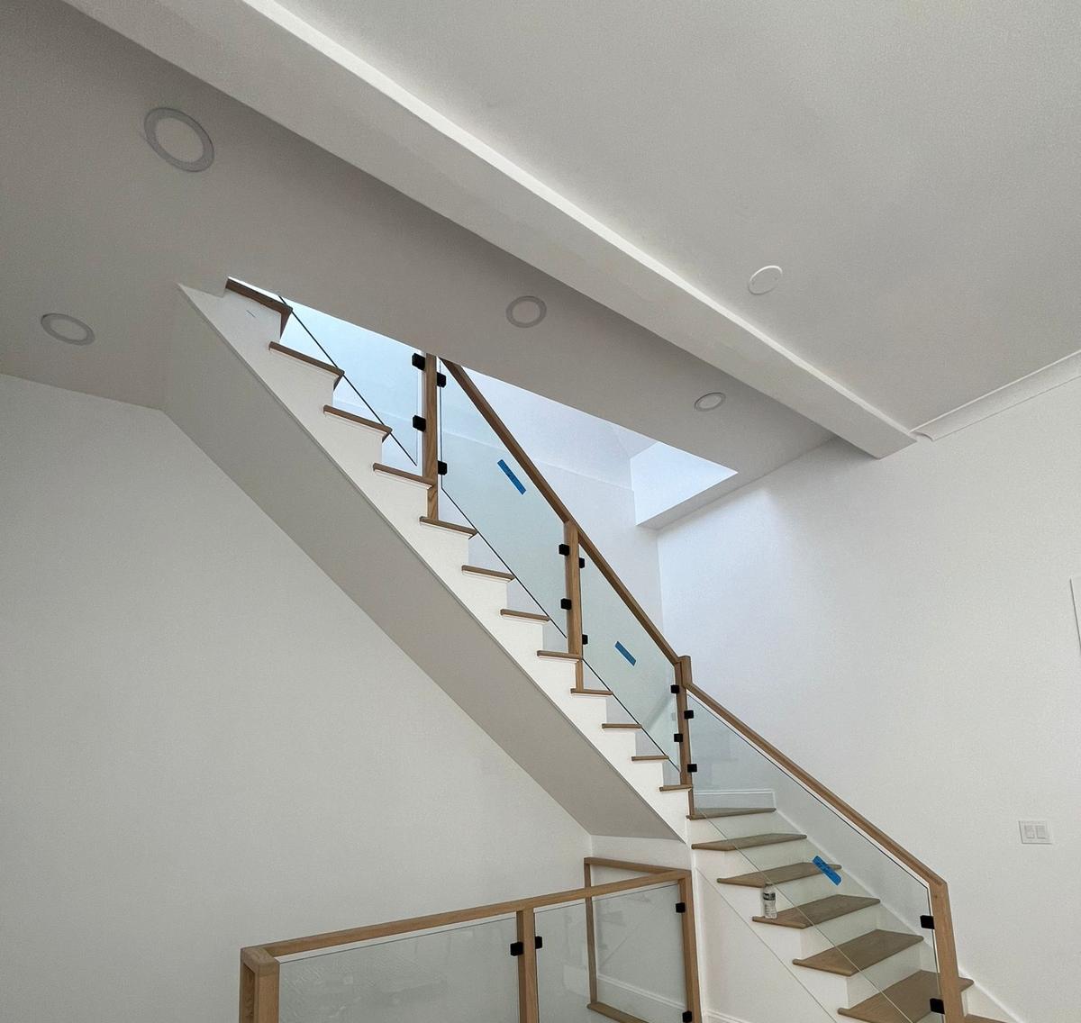 Glass stair and landing railing with wood posts and black clips