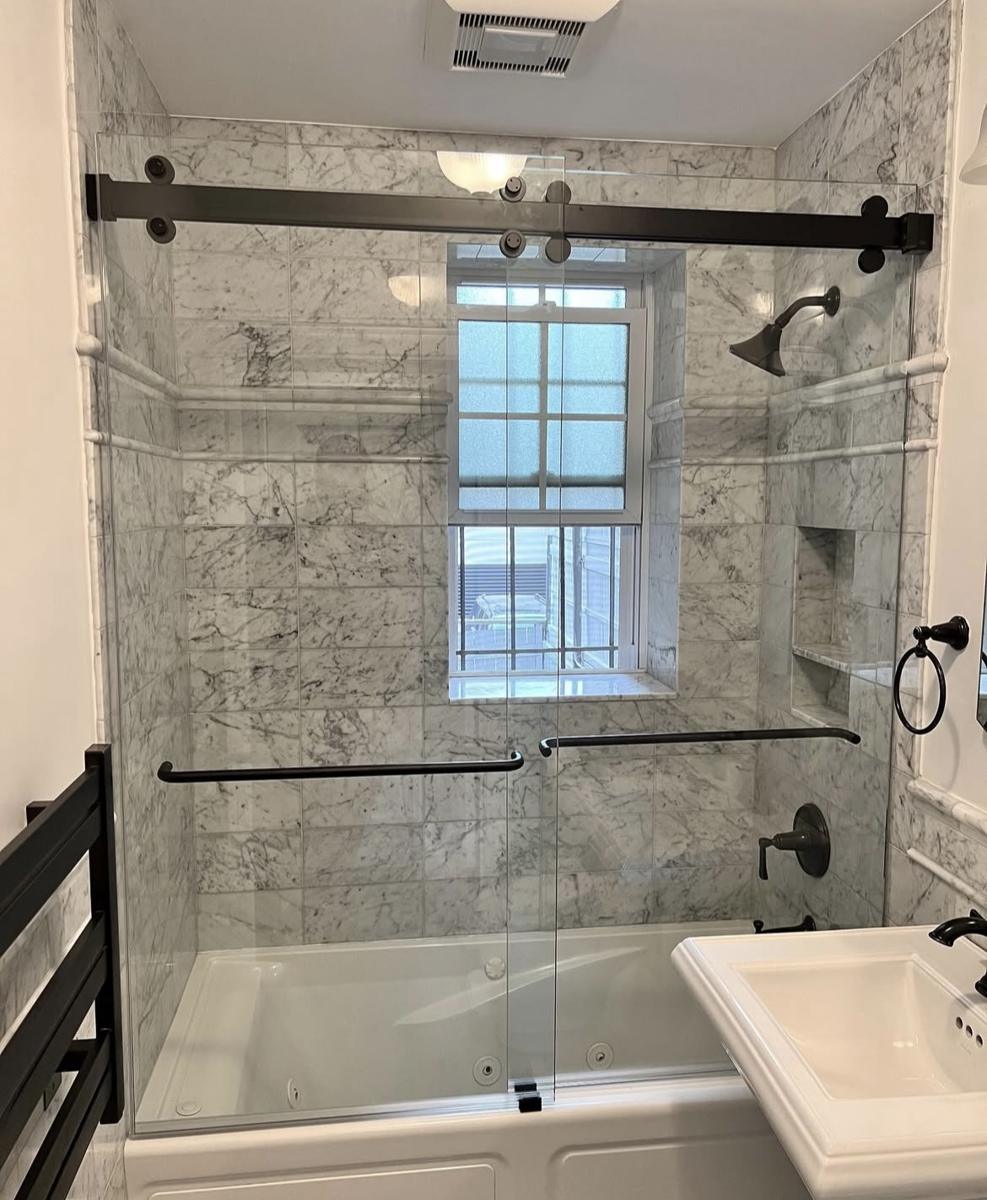 Sliding tub door with oil-rubbed bronze hardware and marble tile