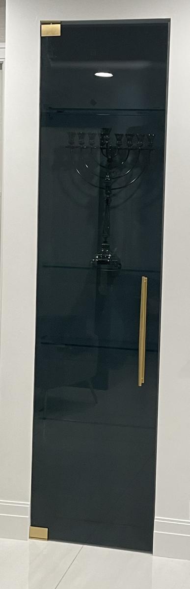 Smoked gray glass cabinet door with brushed gold pivots