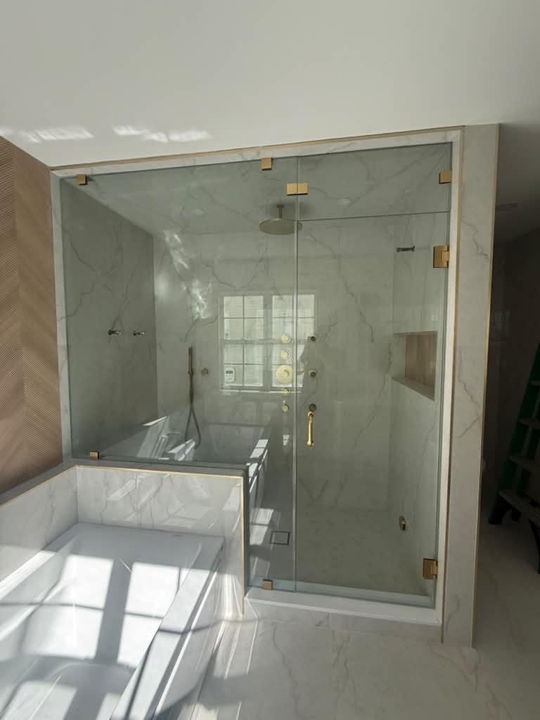 Steam shower with brushed gold hardware over a tub deck
